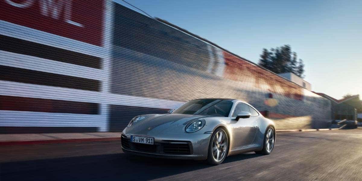 Gray Porsche 911 carrera 4s driving down the street.