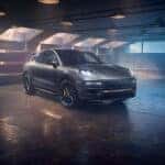 A front three-quarter view of the Porsche Cayenne Turbo GT in a dimly lit garage, showcasing its sleek design, aggressive stance, and cutting-edge lighting features.