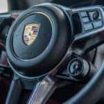 Close-up of a Porsche steering wheel with detailed controls, highlighting the advanced features and engineering behind the PDK transmission system.