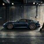 A Porsche 911 Turbo S parked in an industrial-style garage, highlighting its sleek profile, large alloy wheels, and aggressive stance.
