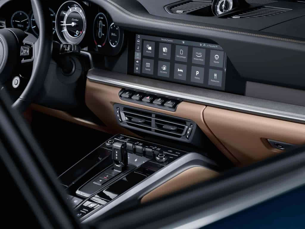 The luxurious interior of the Porsche 911 Turbo S featuring a high-tech digital display, leather upholstery, and an advanced infotainment system.