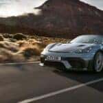 Porsche 918 Spyder driving through a desert highway with mountains in the background, showcasing its sleek design and high-performance stance.