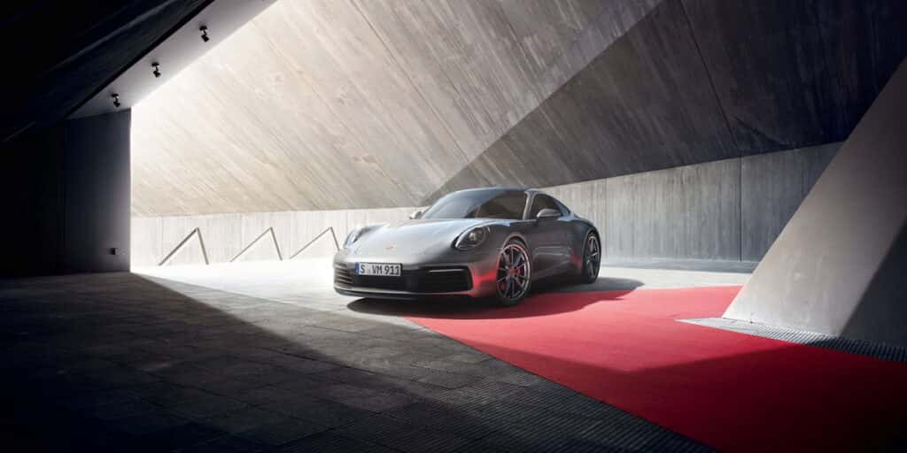 Silver Porsche 911 showcased under modern architecture, highlighting Porsche 911 top speed performance and luxury design.