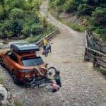 Orange Porsche Macan parked in nature with bikes, helping answer the question: is the porsche macan reliable for active lifestyles.
