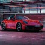 Red porsche targa parked in a modern urban setting at dusk under red neon lighting.