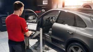 Certified Porsche Technician using specialized diagnostic equipment.
