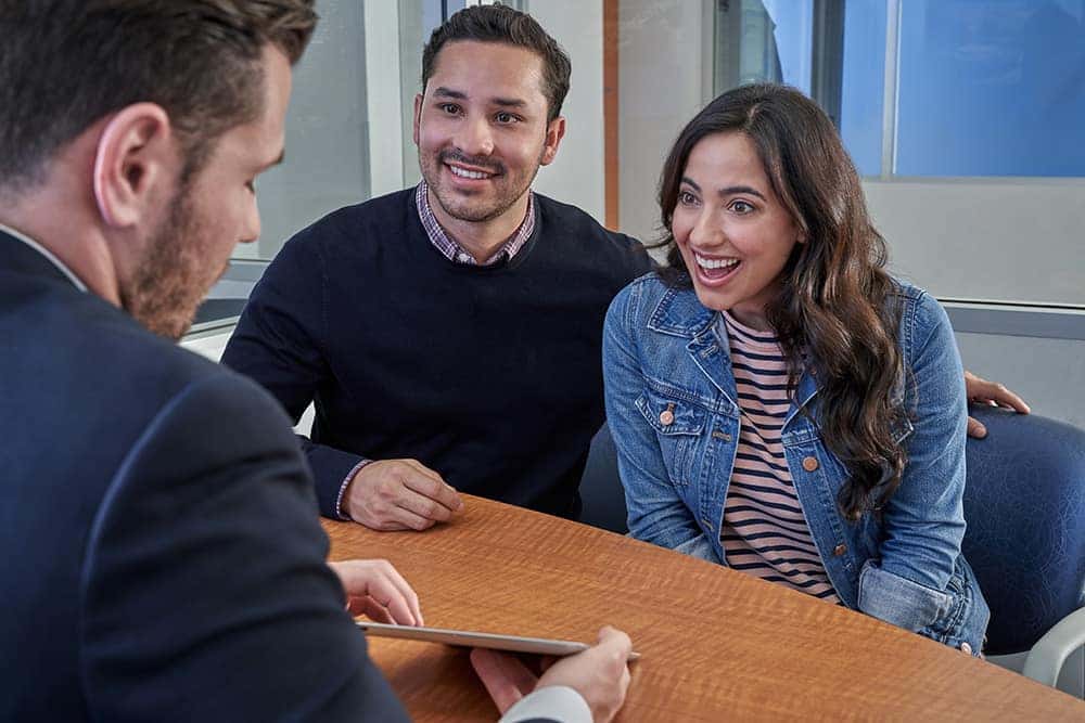 Young happy couple financing a car with a salesman