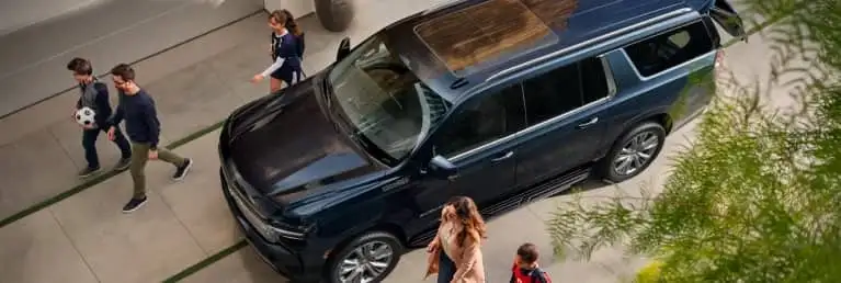 A family walking towards a Chevrolet vehicle in the driveway.
