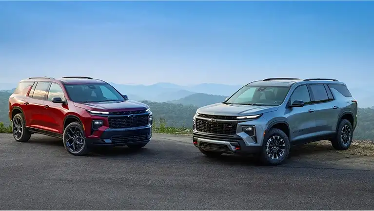 A red and silver Chevrolet SUV facing each other outside on a road near hills