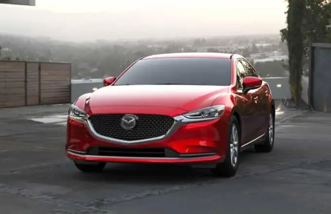 A red Mazda sedan is parked in a parking lot