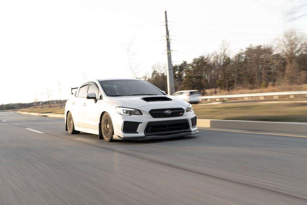 white subaru impreza driving down a road
