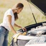 Troubled young woman near broken automobile in countryside during car accident