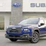 A blue 2026 Subaru Outback Wilderness parked on the front line outside the Sport Subaru South showroom