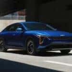 Blue-2025-Kia-K4-driving-under-overpass