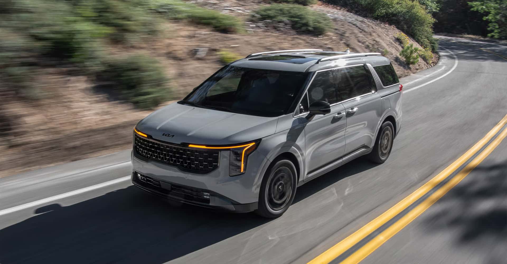 2026 Kia Carnival Hybrid driving down winding road