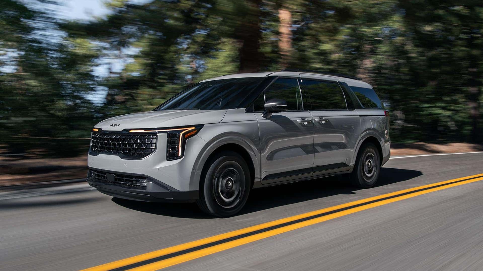 Gray 2026 Kia Carnival Hybrid driving down the road
