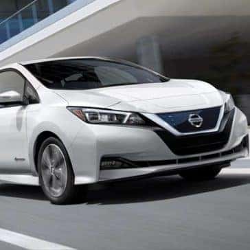 2019 Nissan Leaf driving by a building in the city