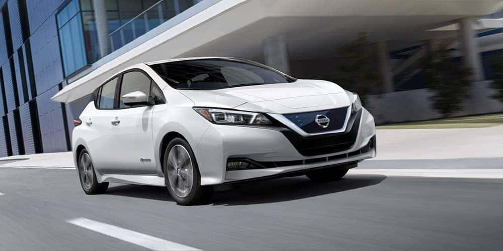 2019 Nissan Leaf driving by a building in the city