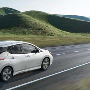 2019 Nissan Leaf driving by grassy fields