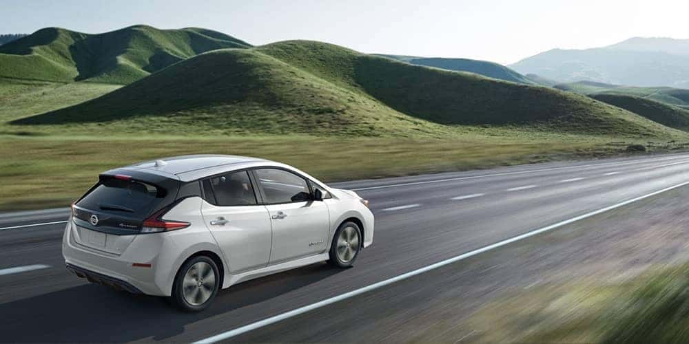 2019 Nissan Leaf driving by grassy fields
