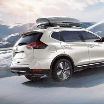 2020 Nissan Rogue driving on a snowy road in the mountains