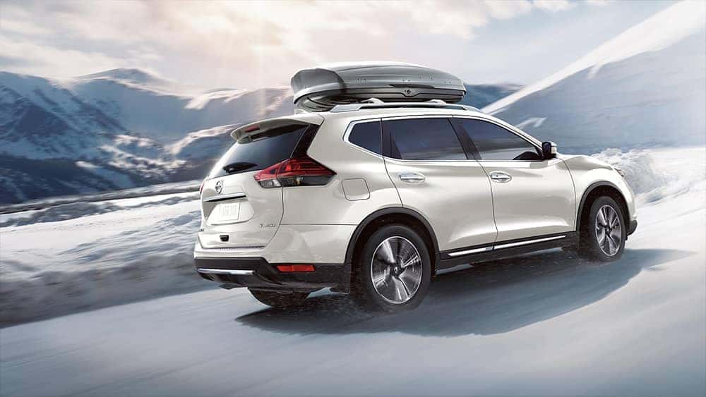 2020 Nissan Rogue driving on a snowy road in the mountains