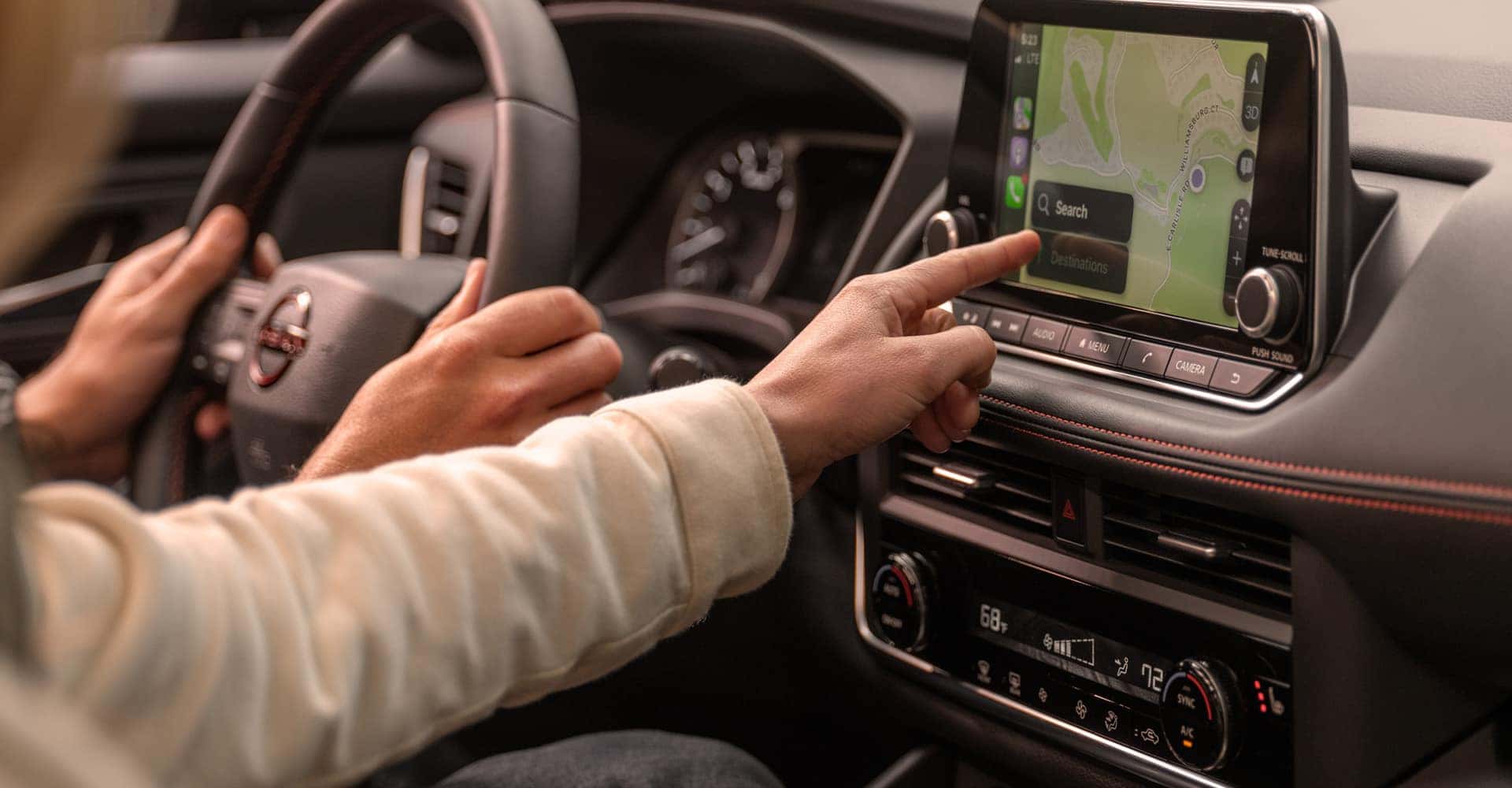 Person Pointing to Nissan Rogue GPS Screen width=