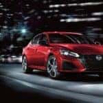 Red 2025 Nissan Altima drtiving down city street at night