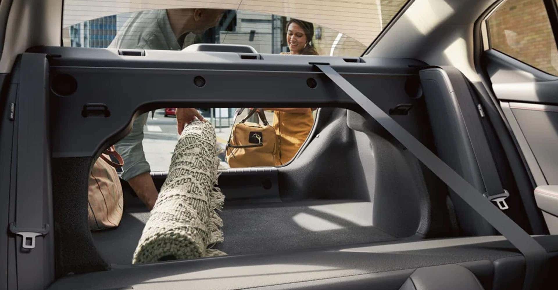 2025-nissan-sentra-displaying-people-putting-rug-into-cargo-space