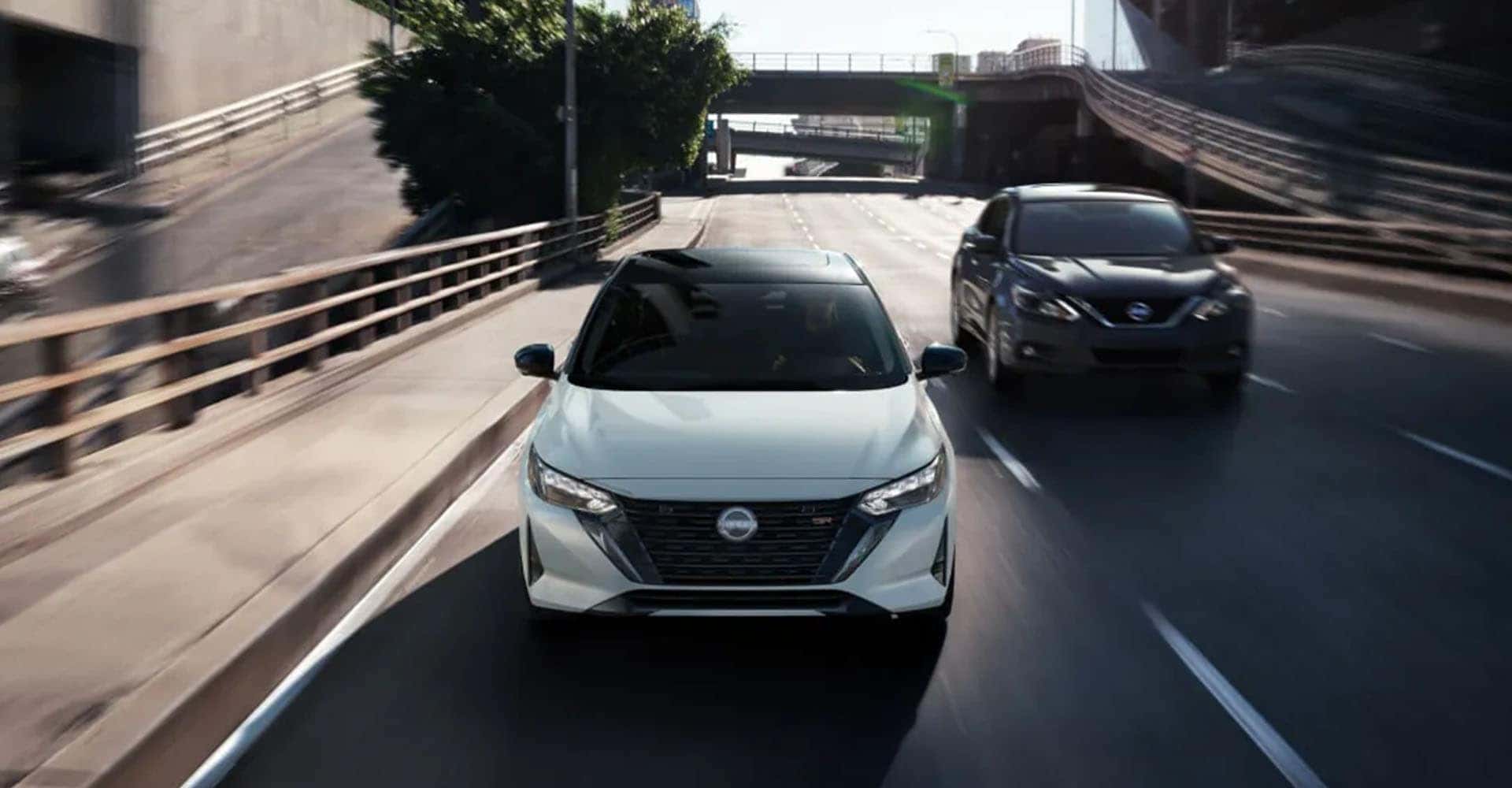2025-nissan-sentra-front-view-white-driving-through-city-streets