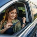business woman sitting in a car putting on her seat belt