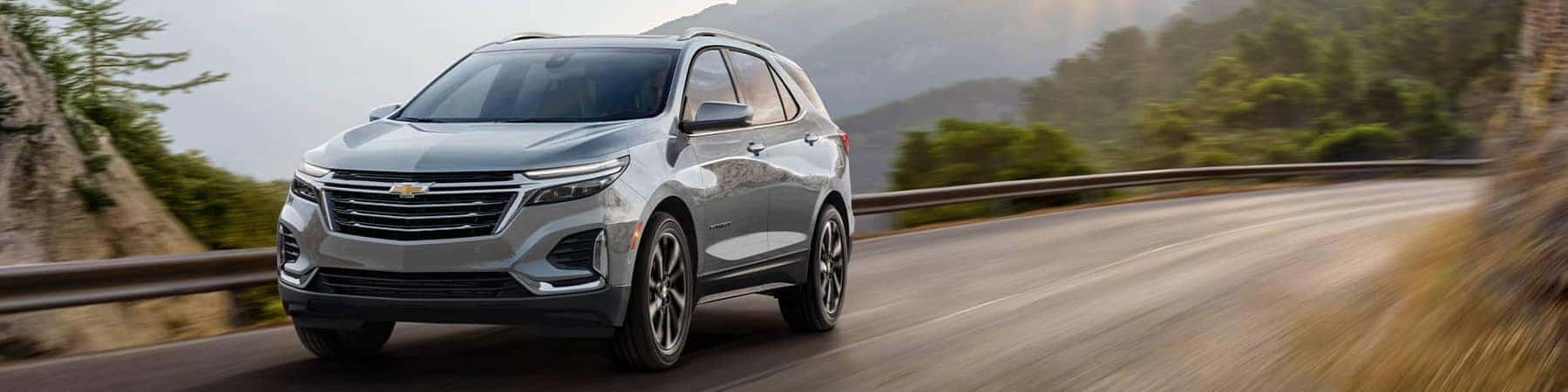 2023 Silver Chevrolet Equinox on a mountain road at sunrise