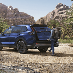 An exterior shot of a person closing a Honda SUV trunk