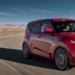 Red Kia Soul racing around highway curve in the desert