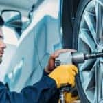 Mechanic removing lug nuts from tire using a tool