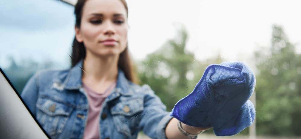 Woman using microfiber cloth to clean car windshield