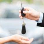 Woman buying a car and sales person handing her car keys