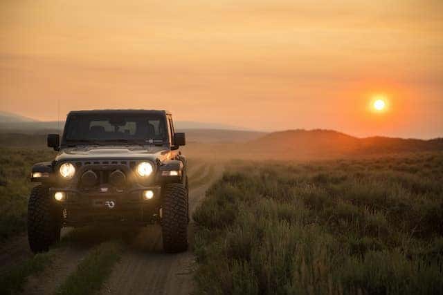 jeep driving through nature at sunset